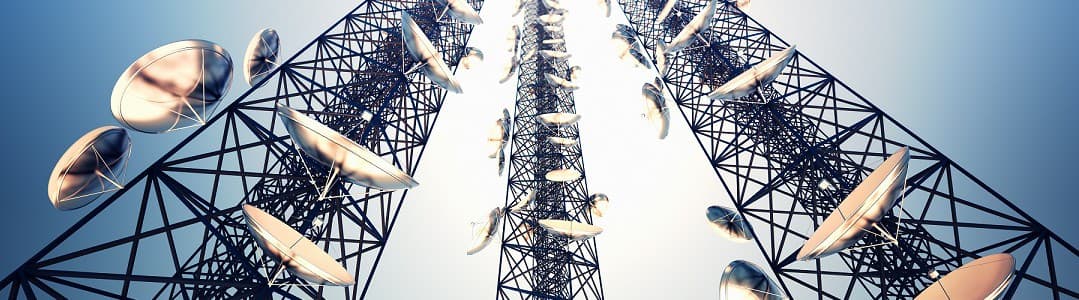 Tall tower with multiple satellite dishes against a clear sky.
