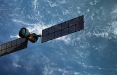 Satellite with solar panels against a blue sky with clouds.