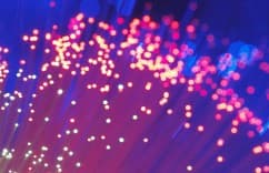 Abstract purple and pink bokeh light streaks with glowing dots on a dark background.