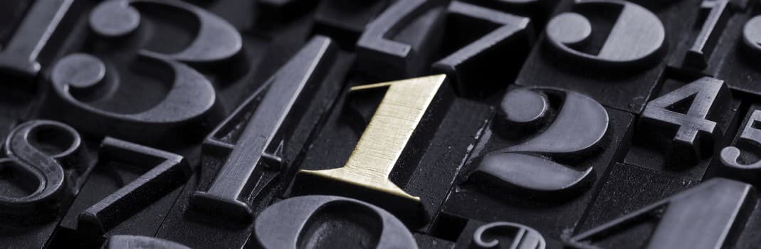 Gold number '1' among black letterpress blocks on a dark background.