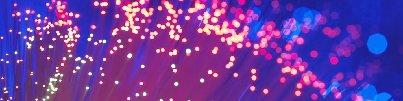 Abstract purple and pink bokeh light streaks with glowing dots on a dark background.