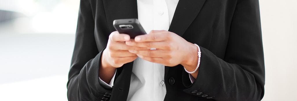 Torso of a man in a suit, holding a mobile phone